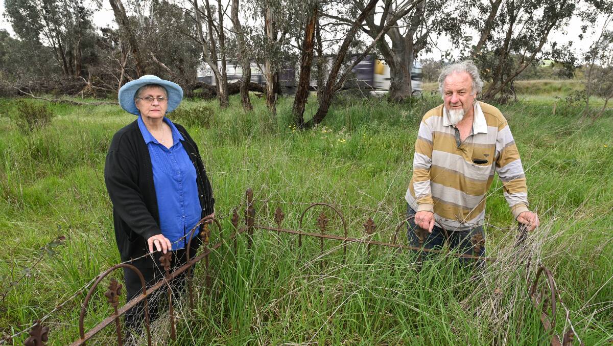 Holbrook residents Elaine Strong and John Lynch stand in front of a fenced off grave with no name at the Little Billabong Cemetery between the north and soundbound lanes of the Hume Highway, north of Holbrook. Picture by Mark Jesser