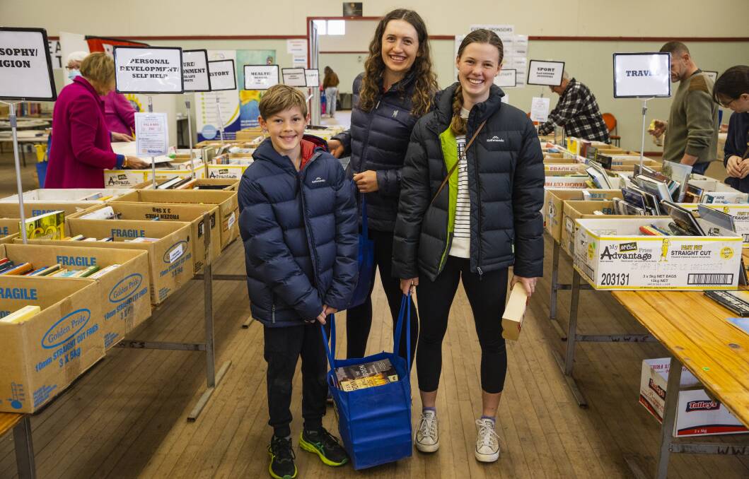 Alex Miller, 12, Jemima Donovan, 22, and Kate Miller, 14. Alex and Kate collected so many books they needed to carry the bag together. Pixcture by Ash Smith