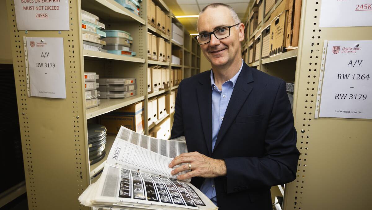 CSU Regional Archives manager Wayne Doubleday flicking through contact sheets and film negatives from The Daily Advertiser in 1994. Picture by Ash Smith