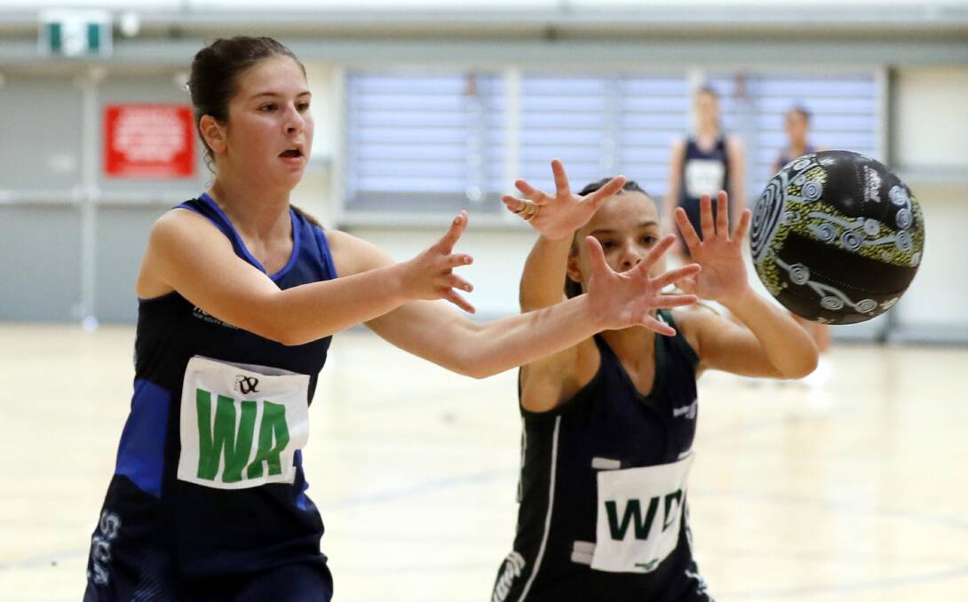 Sophie Cross receives a pass during Southern Sport Academy's game against Hunter Academy of Sport while Halle Clemente tries to intercept. Picture by Les Smith