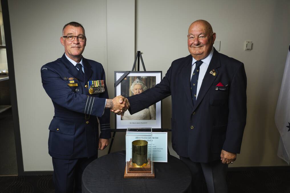 Wing Commander Darren Dolan presents a casing from a 96-gun salute to mark the passing of Queen Elizabeth II to Junee RSL sub-branch president Greg Zakharoff. Picture by Ash Smith