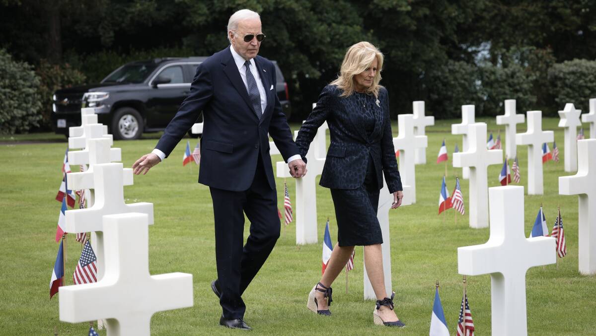 US President Joe Biden, with wife Jill, reaches out to touch a US soldier's tombstone while touring the Normandy American Cemetery on the 80th anniversary of D-Day. Picture Getty Images