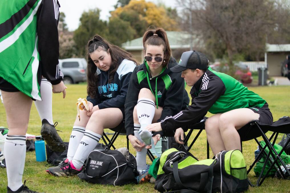Braeleigh Newton fuels up as Caitlin Willcox is helped by Jessica Fordree strapping her ankle before South Wagga's Madden Shield game against Tolland White at Forest Hill Oval. Picture by Madeline Begley