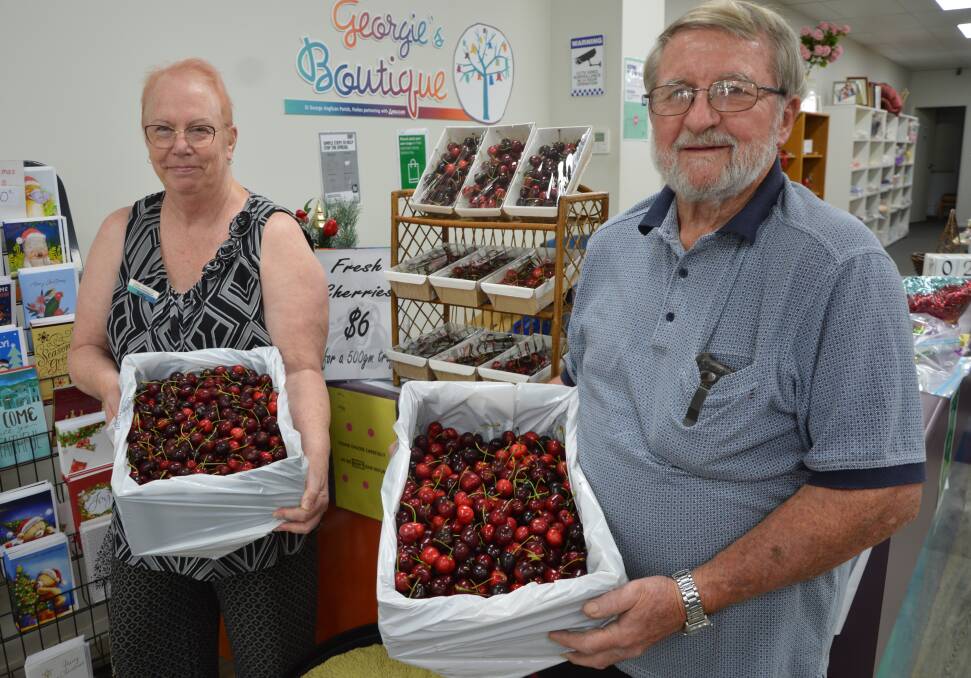 Georgie's Boutique volunteer Kathy Madden and Keith Woodlands in Parkes with the five kilogram cartons and packages of cherries from Young that are being sold to raise money for flood victims this year. Picture by Christine Little